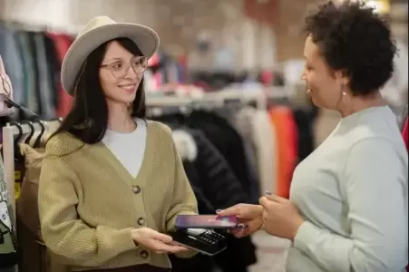 atendente mulher passando maquina de cartão para cliente pagar - atendimento ao cliente