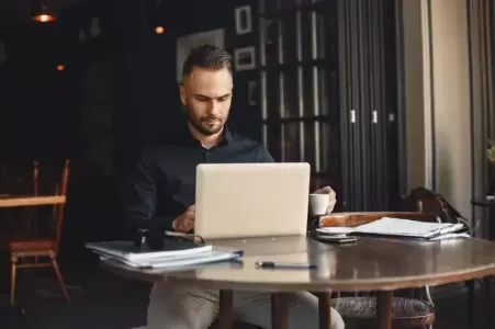 homem de negócios tomando café e trabalhando no computador - gestão de empresas