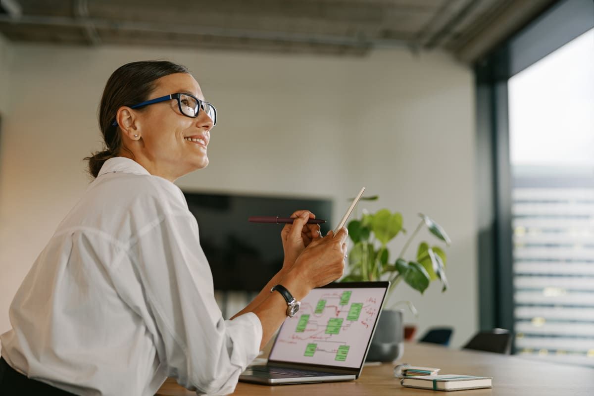 Mulher sorridente analisa gráficos em laptop, simbolizando planejamento estratégico para negócios lucrativos em 2025 no ambiente corporativo.