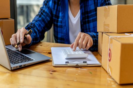 Lojista faz contas em coputador para definir a precificação de produtos