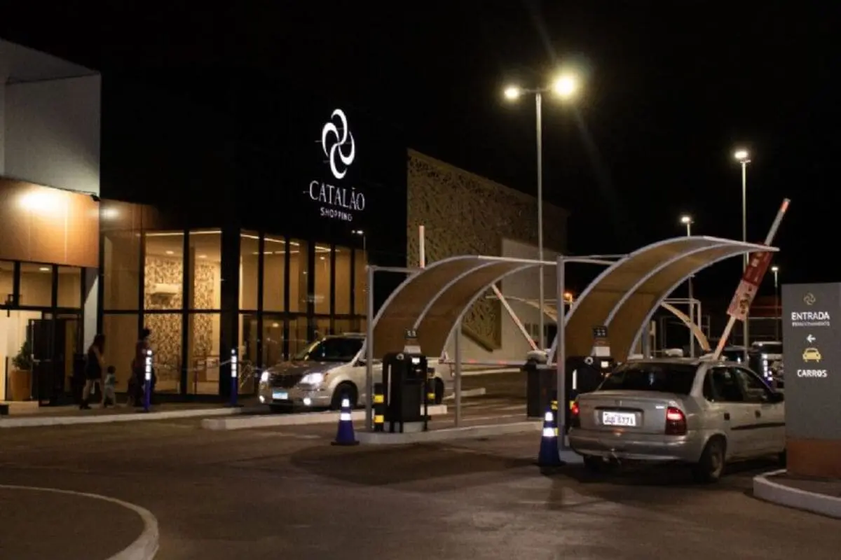 Fachada iluminada e entrada de estacionamento com carros à noite, mostrando diferenciais do Catalão Shopping.