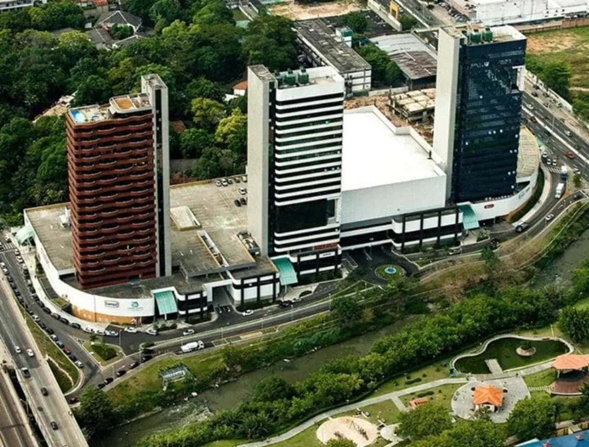 Vista aérea do complexo comercial e torres do Millennium Shopping cercado por área verde.