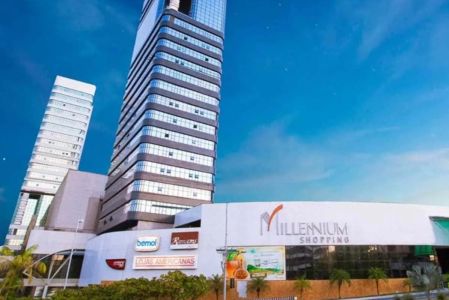 Fachada externa do Millennium Shopping com torres empresariais e letreiro em dia ensolarado.