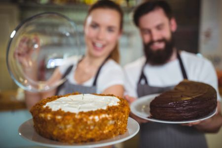 casal faz propaganda de franquia de bolos enquanto seguram bolos