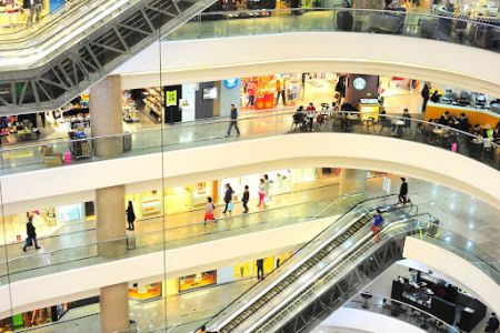 Vista dos andares de um grande shopping e suas lojas, que podem ser alugar através de uma plataforma de locação em shopping.
