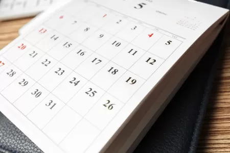 Calendário mensal aberto sobre uma mesa de madeira.