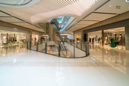 Interior amplo e moderno de um shopping de luxo com lojas de roupas e escadas rolantes, exemplificando o conceito de Res sperata.